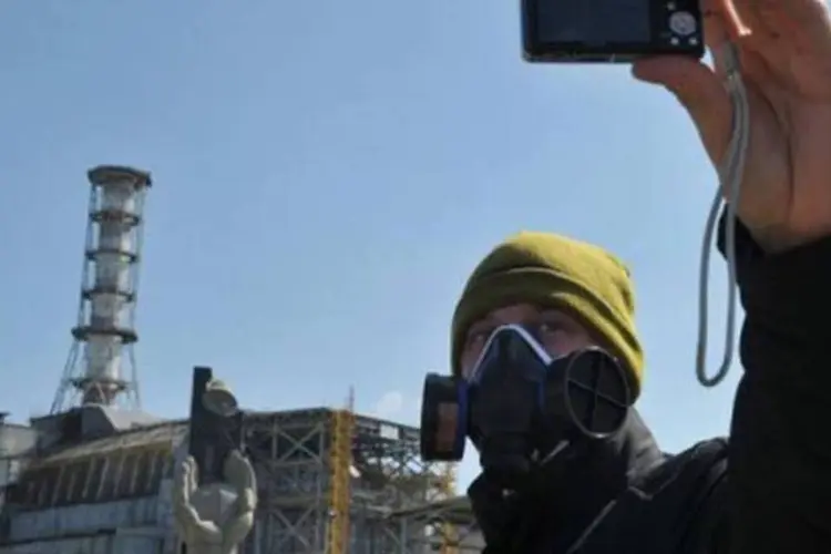 Turista tira fora em frente a usina de Chernobyl, na Ucrânia (Sergei Supinsky/AFP)