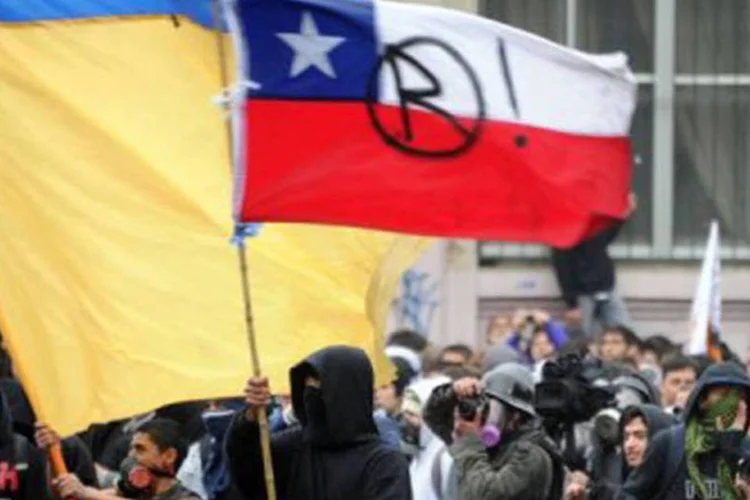 
	Estudantes protestam em Santiago, no Chile: centenas de jovens, a maioria deles encapuzados, arrancaram sinais, lixeiras, paralelep&iacute;pedos, bancos de parque e algumas das cercas met&aacute;licas das ruas
 (Martin Bernetti/AFP)