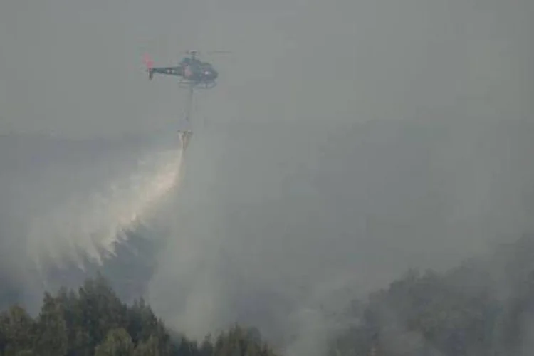 
	Um helic&oacute;ptero dos bombeiros tenta controlar o fogo em inc&ecirc;ndio florestal em Valpara&iacute;so, Chile
 (VLADIMIR RODAS/AFP)