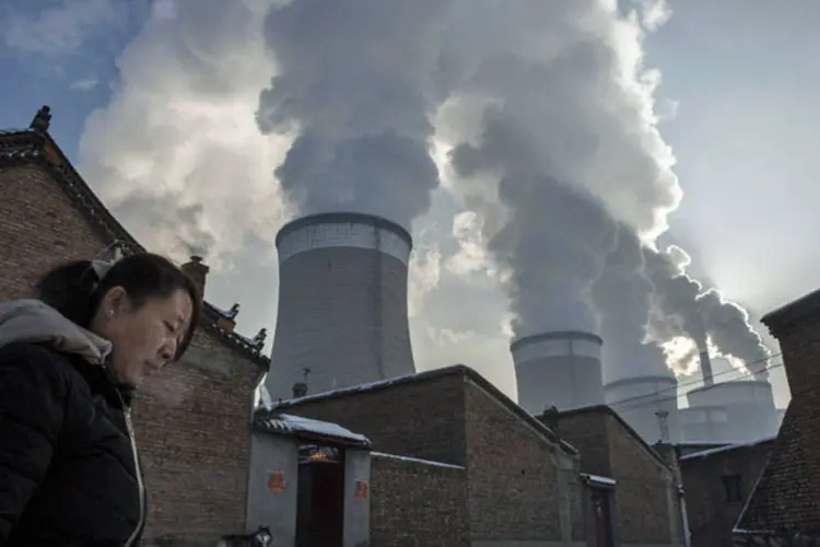 Perigo no ar: mulher caminha na rua de sua casa, que fica ao lado de uma usina a carvão, em Shanxi, na China. (Getty Images)