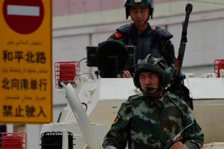 Polícia chinesa anda em veículos blindados durante uma cerimônia de demonstração de força em Urumqi (Mark Ralston/AFP)