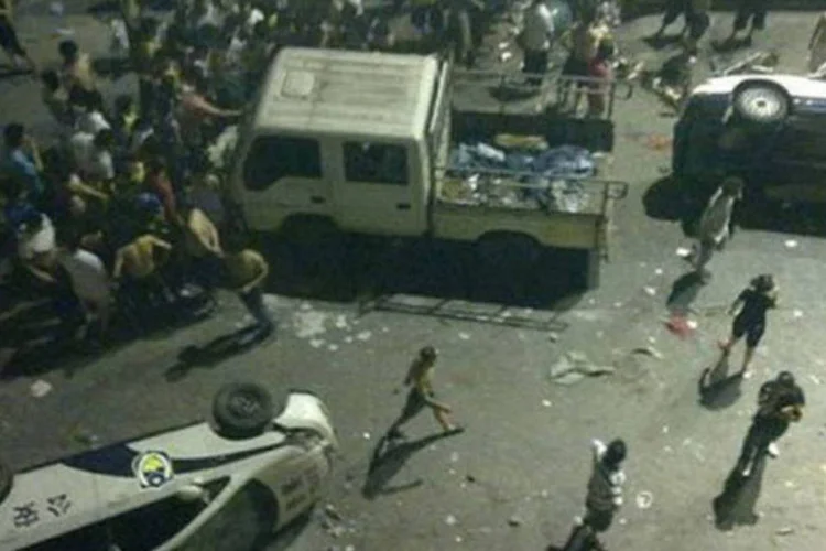Imagem mostra carros depredados durante protesto em Xintang, quando centenas atacaram policiais com paus e pedras.
 (AFP)