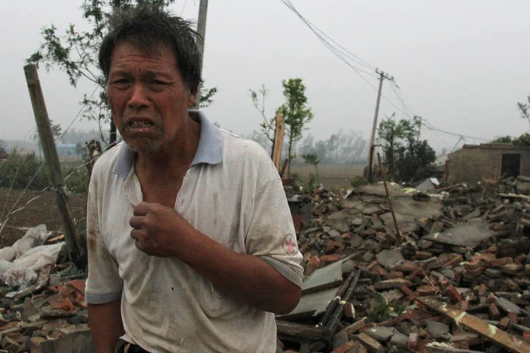 
	Homem perto de pr&eacute;dios destru&iacute;dos por tornado na China
 (China Daily / Reuters)