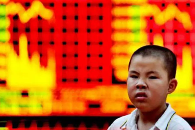 Menino chinês passa em frente a painéis com a cotação da bolsa em Xangai, China: mercados internacionais reagiram mal ao PIB (Philippe Lopez/AFP)
