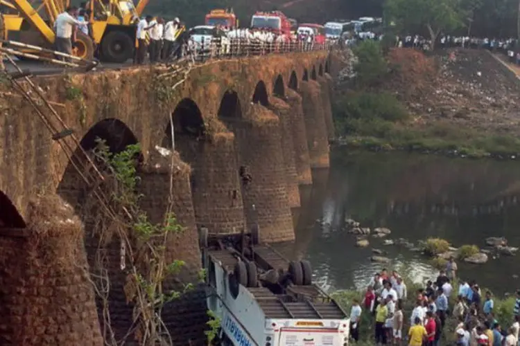Equipes de resgate trabalham em destroços de ônibus que caiu de ponte na Índia (AFP)