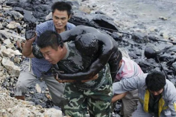Desespero no porto de Dalian, na China: um bombeiro morre e outro é resgatado com vida após tentativa de contenção do vazamento de petróleo.   (.)