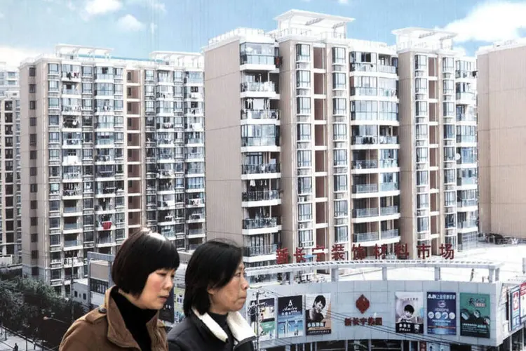 
	Chinesas caminham em frente &agrave; an&uacute;ncio de complexo de apartamentos em Xangai
 (Qilai Shen/Bloomberg)