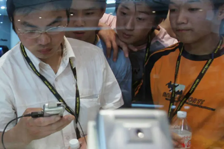 Chineses olham para celular: um dos setores que deve se beneficiar das tecnologias móveis é o das empresas de serviços públicos e de serviços essenciais (Getty Images)