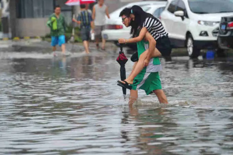 Homem carrega mulher em rua inundada em Haikou, na província de Hainan, na China (ChinaFotoPress/Getty Images)