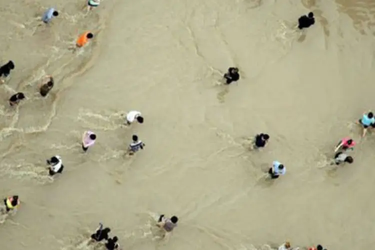 Chineses caminham na enchente em Lanxi: mais de um milhão de pessoas foram retiradas de suas casas na semana passada


 (AFP)