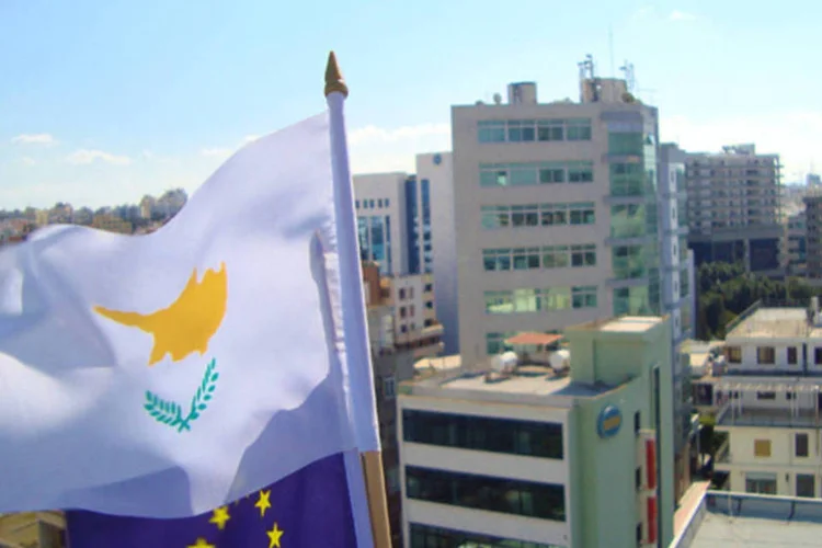 Bandeiras do Chipre e da União Europeia em prédio: o resgate passará por um programa completo de reformas e compromissos (EUCyprus/Wikimedia Commons)