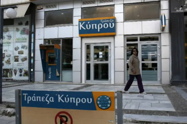 
	Mulher caminha em frente a ag&ecirc;ncia do Banco do Chipre: pelo menos duas grandes institui&ccedil;&otilde;es financeiras gregas mostraram interesse nas unidades cipriotas
 (REUTERS/Yorgos Karahalis)