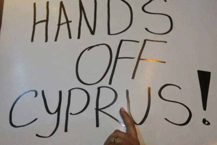 Manifestante levanta um cartaz durante um protesto de funcionários do Banco Popular do Chipre no exterior do Parlamento, em Nicósia (REUTERS/Yannis Behrakis)