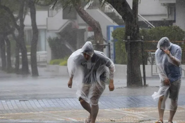 Pessoas caminham em meio a forte chuva causada pelo tufão Vongfong, no Japão (Kyodo/Reuters)