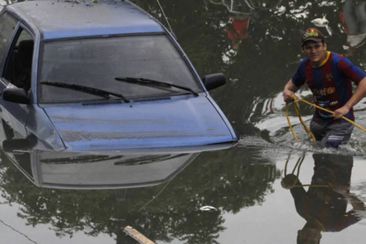 Homem tenta tirar o seu carro de uma rua alagada após as fortes chuvas em Cali, na Colômbia (Jaime Saldarriaga/Reuters)