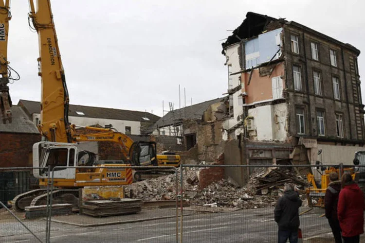 Pedestres passam por prédios sendo demolidos na cidade de Hull, norte do Reino Unido (Simon Dawson/Bloomberg)