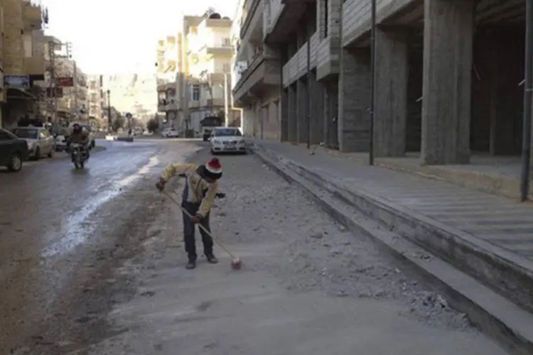Menino varre a rua próximo a prédio danificados pelo que ativistas disseram ter sido um bombardeio de forças leais ao presidente da Síria, Bashar al-Assad, em Yabroud, próximo a Damasco (Shaam News Network/Divulgação via Reuters)