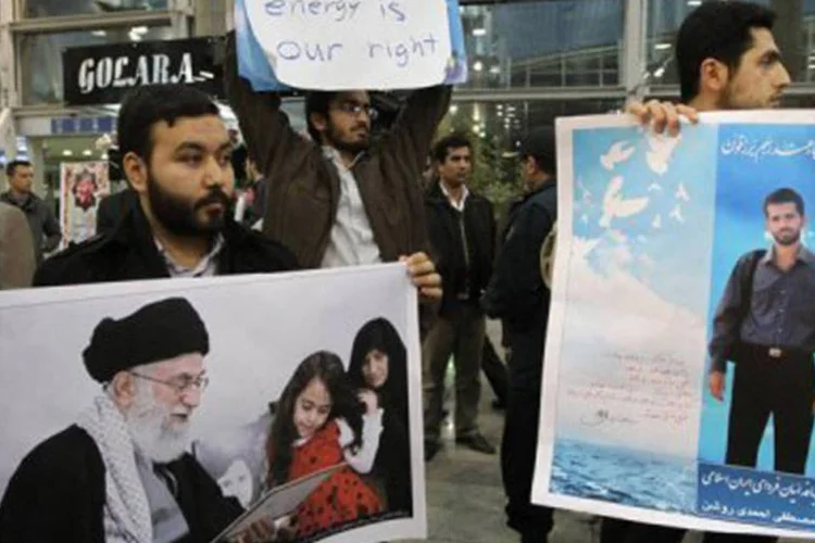 Estudantes iranianos, no aeroporto de Teerã, com cartazes de cientistas nulceares assassinados: depoimentos exibidos em TV estatal do Irã acusam Israel pela morte dos profissionais (Atta Kenare/AFP)