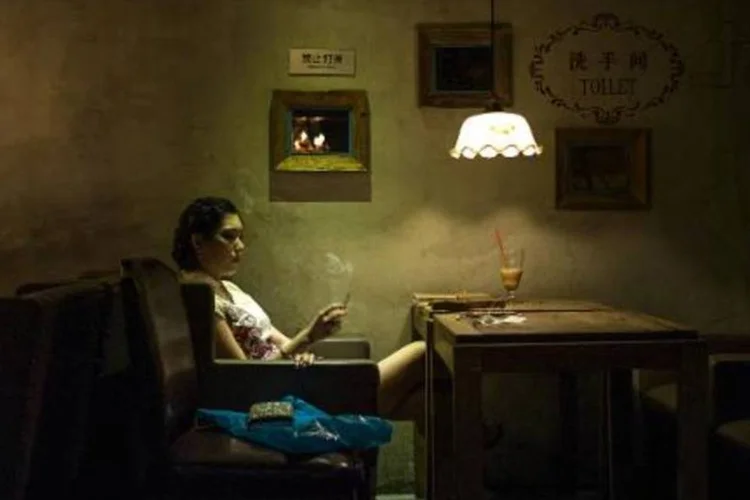 Mulher fuma cigarro em bar de Pequim (FRED DUFOUR/AFP)