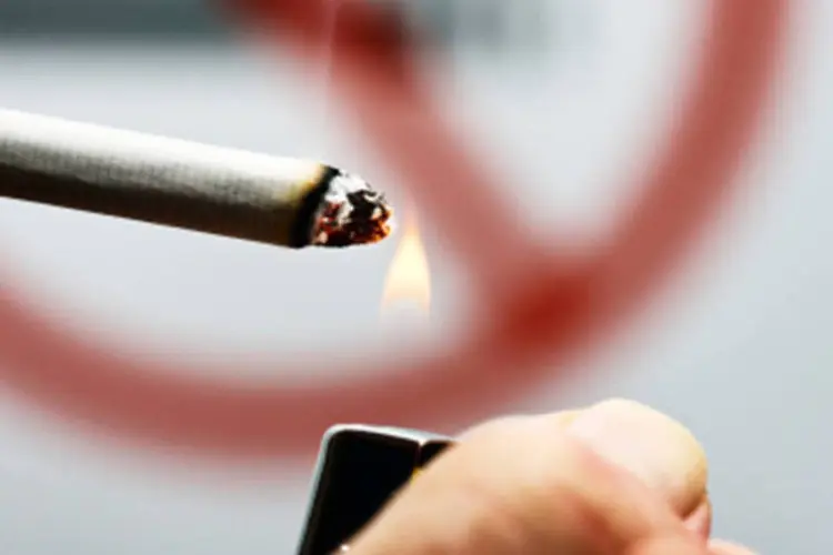 Pessoa fumando na frente de aviso que proíbe cigarro: a situação com menor reprovação social é a compra de produtos piratas (64%). (GettyImages)