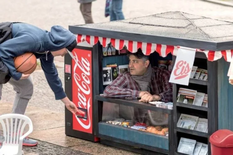 Ação da Coca-Cola: atendente que enfiou as pernas no chão para também aparecer em sua versão mini (Reprodução/YouTube)