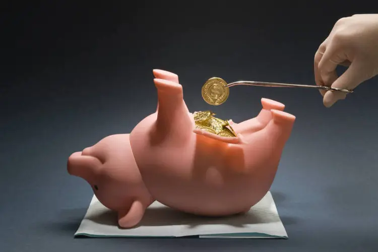 Imagem de um médico mexendo em um cofrinho, representando o conceito de saúde financeira (Thinkstock/Jupiterimages)