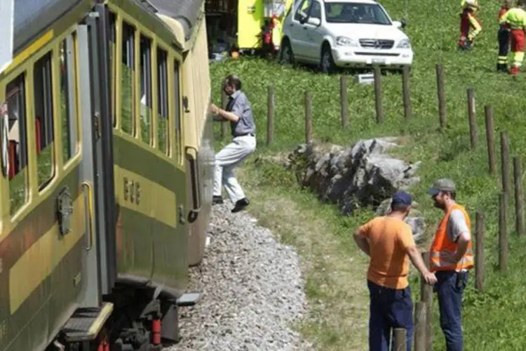 
	Homens trabalham na cena de um acidente de trem, em Gsteigwiler, na Su&iacute;ca, em 2003: a evacua&ccedil;&atilde;o dos passageiros durou cerca de duas horas, disse a pol&iacute;cia (Markus Hubacher/AFP)