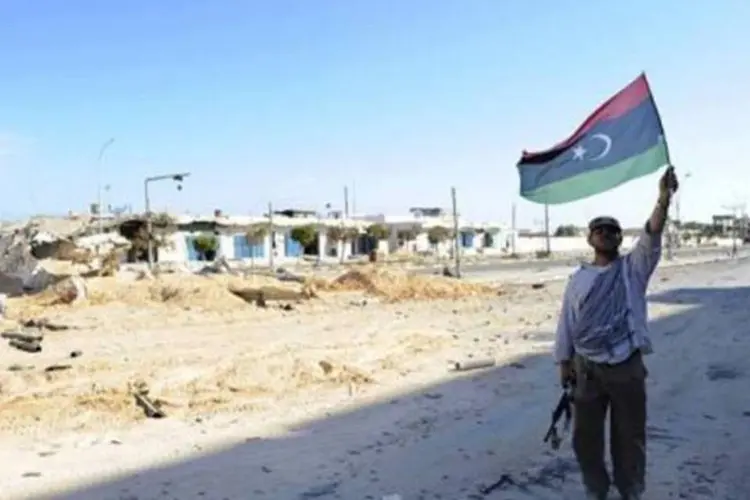 Combatente usa uma bandeira rebelde para comemorar a morte de Kadafi:  2,8 milhões de líbios estão cadastrados para votarem na escolha do CNG (Philippe Desmazes/AFP)