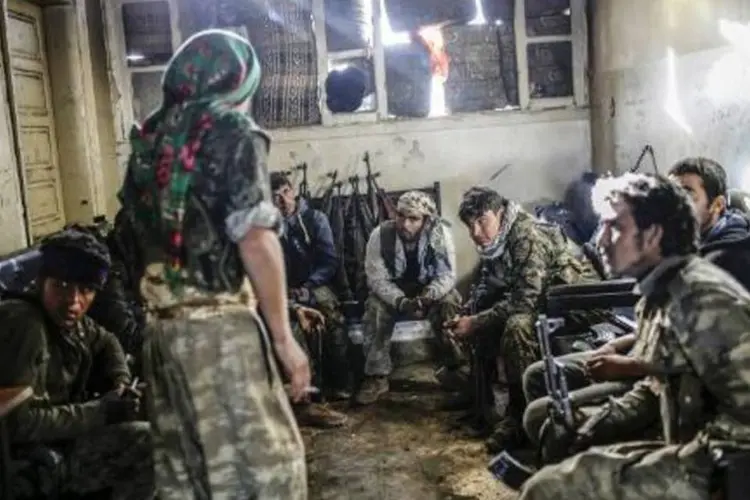 Combatentes curdos se refugiam em uma casa da cidade síria de Kobane, de onde expulsaram o Estado Islâmico (Yasin Akgul/AFP)