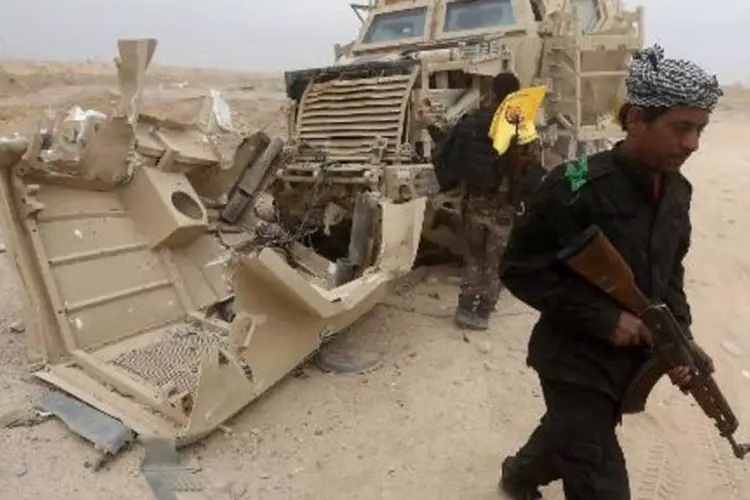 Combatentes xiitas inspecionam um veículo destruído por militantes jihadistas nos arredores de Tikrit (Ahmad al-Rubaye/AFP)