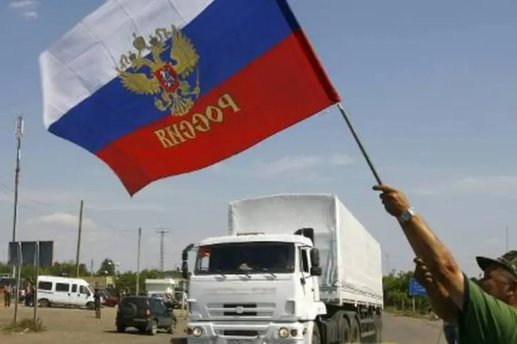 
	Morador agita bandeira russa, durante passagem de comboio pela fronteira
 (Sergey Venyavksy/AFP)