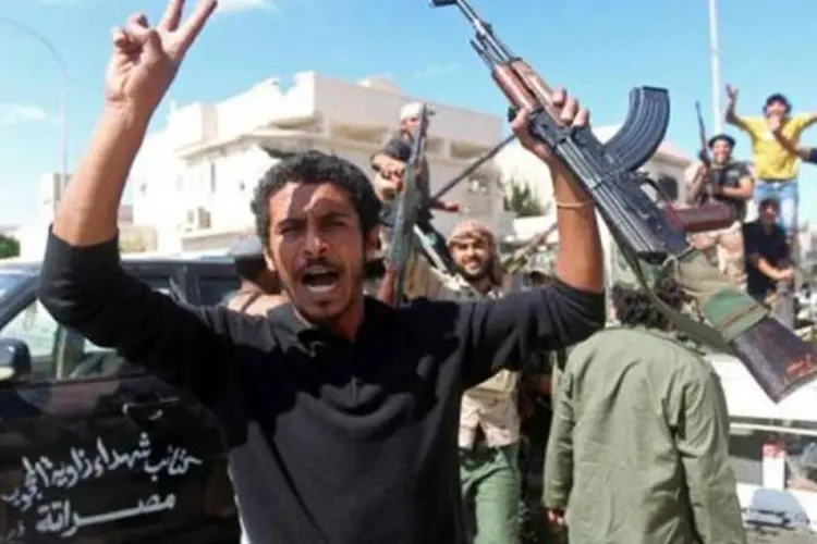 Combatentes líbios comemoram a morte de Kadafi em Sirte: fim de um 'longo e sombrio capítulo' disse a Otan (Ahmad al-Rubaye/AFP)