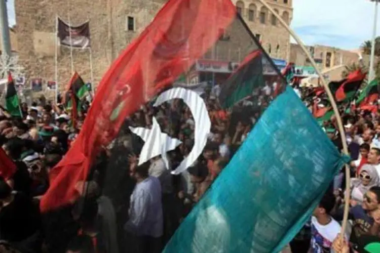 Líbios com a bandeira rebelde comemoram a morte de Kadafi em Trípoli (Mahmud Turkia/AFP)