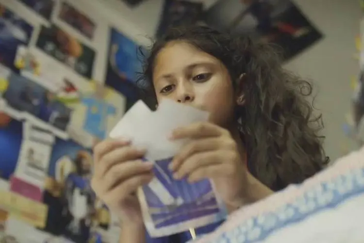 Comercial HSBC: uma menina por volta dos seus 12 anos que só quer saber de completar seu álbum de figurinhas com seu grande ídolo (Reprodução)