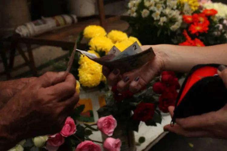 
	Consumidora entrega dinheiro para vendedor de flores: o com&eacute;rcio foi o setor que apresentou maior incid&ecirc;ncia de reajustes com ganhos reais em 2013
 (Dado Galdieri/Bloomberg)