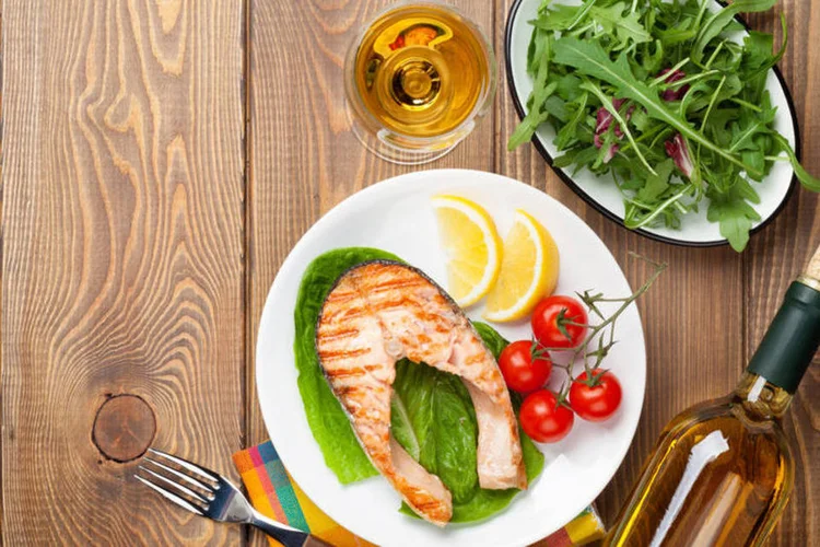 Prato com peixe acompanhado a uma taça de vinho (Thinkstock)