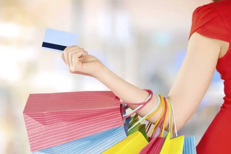 Mulher com sacolas e cartão de crédito (Thinkstock)