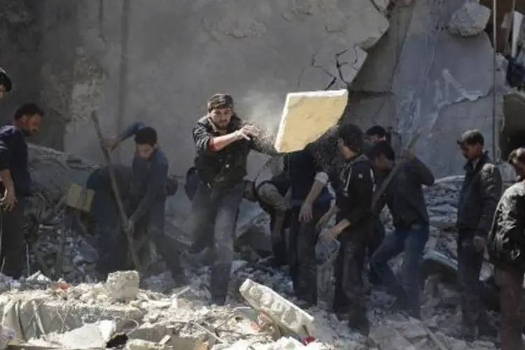 Sírios buscam sobreviventes em meio a destroços na área de Douma, a leste de Damasco (Sameer al-Doumy/AFP)