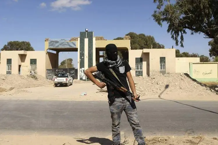 
	Militante patrulha a entrada da sede da mil&iacute;cia Fevereiro 17 depois que for&ccedil;as irregulares l&iacute;bias entraram em confronto, em Benghazi, no leste da L&iacute;bia
 (Esam Omran Al-Fetori/Reuters)