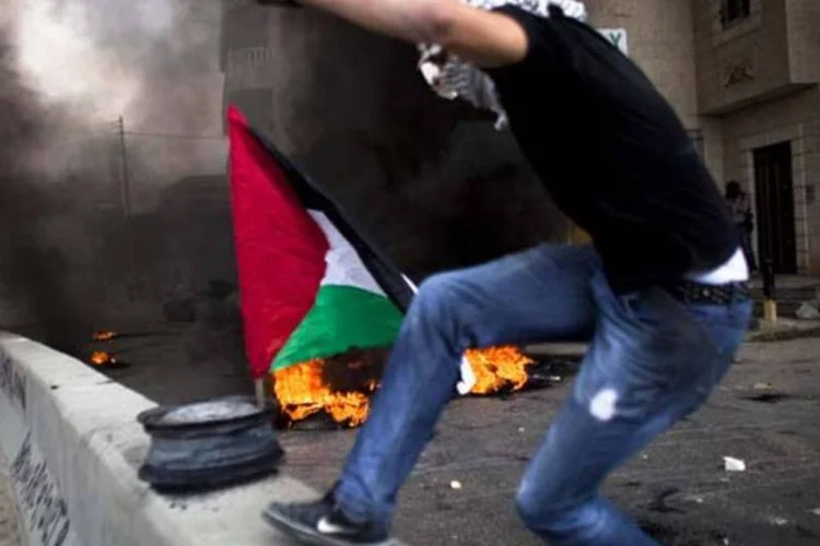 Manifestante palestino enfrenta polícia de Israel com pedras durante confronto em Ramala (Uriel Sinai/Getty Images)