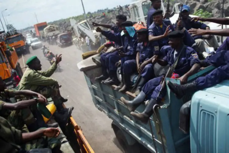 Rebeldes do M23 passam por um caminhão com policiais durante a sua retirada de Goma, na República Democrática do Congo (©afp.com / Phil Moore)