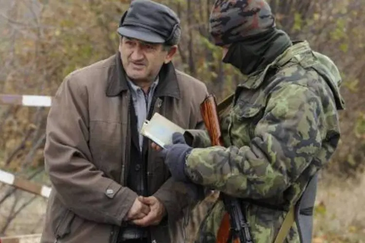 Soldado ucraniano verifica a identidade de um homem em um posto na cidade de Bugas, leste do país (Alexander Khudoteply/AFP)
