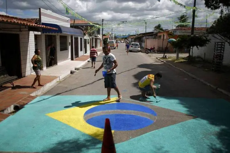 Moradores pintam uma bandeira do Brasil em uma rua próxima do aeroporto de Natal (Carlos Barria/Reuters)