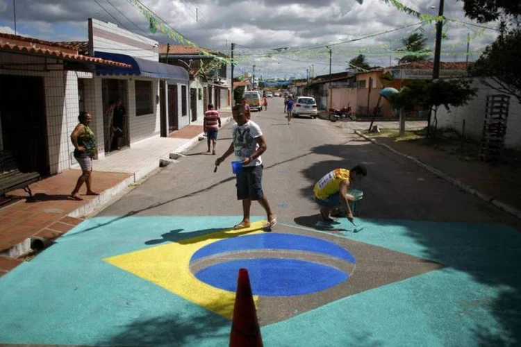 Moradores pintam uma bandeira do Brasil em uma rua próxima do aeroporto de Natal, no Rio Grande do Norte (Carlos Barria/Reuters/Reuters)