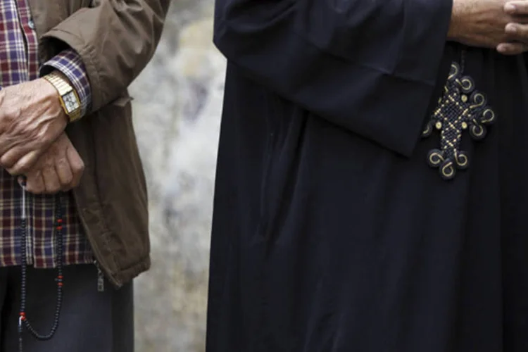 
	Homem mu&ccedil;ulmano segurando um ter&ccedil;o e um crist&atilde;o coopta vestindo uma cruz aguardam em uma fila para votar no referendo da nova constitui&ccedil;&atilde;o do Egito, em Cairo
 (Amr Abdallah Dalsh/Reuters)