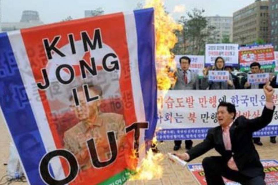 Manifestante sul-coreano queima bandeira da Coreia do Norte com foto de Kim Jong-Il (Jung Yeon-Je/AFP)