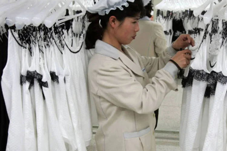 
	Funcion&aacute;ria da f&aacute;brica t&ecirc;xtil Shinwon, no complexo industrial de Kaesong, arruma pe&ccedil;as
 (Chung Sung-Jun/Getty Images)