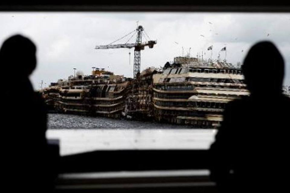 Moradores observam o Costa Concordia no porto de Giglio, na Itália: cruzeiro será provavelmente desmontado na Turquia (Filippo Monteforte/AFP)