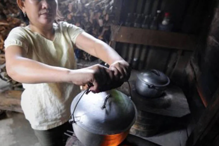 Filipina cozinha para sua família em fogão com carvão em Manilla: ONU lançou associação para estabelecer mercado para cozinhas limpas e combustíveis eficientes
 (Romeo Gacad/AFP)