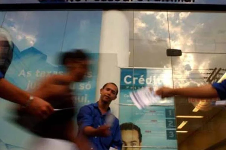 Homem oferece crédito na rua: famílias precisam pagar dívidas para reanimar a economia (.)